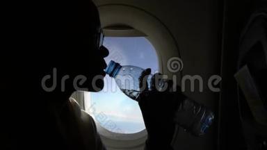 4k亚洲女人在飞行途中拿着透明瓶子喝水