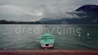 雨天雾山背景下，孤独的薄荷船停泊在安纳西湖的长廊上
