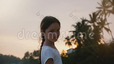 快乐轻松的小6-8岁的<strong>女孩子</strong>回头看镜头，在夕阳下的热带海滨度假。