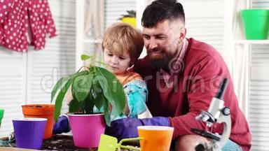 周末快乐。 一对父子。 <strong>滋润</strong>。 男孩把水洒在植物花上。 家庭花园里的实验