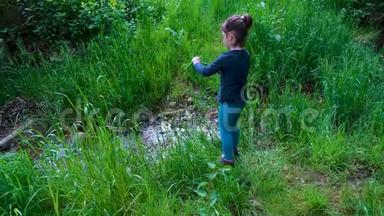 小女孩在大自然中玩着一把刀，在树林里把草切成一条小溪，还有一把求生的刀，工具