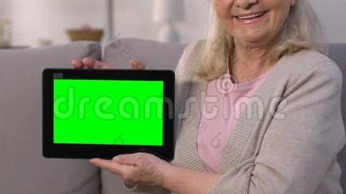 微笑的老太太用绿色屏幕显示平板电脑，快速上网