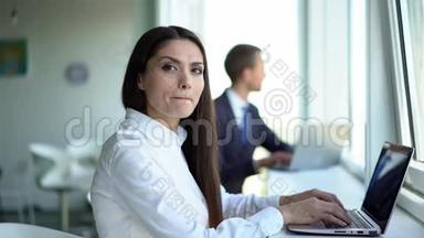 漂亮的女孩正在大光办公室里用笔记本电脑工作