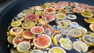 做一杯覆盖的葡萄酒饮料。 橙子、柠檬、葡萄柚和豆蔻的特写镜头，这些东西在热水表面，而且是沸腾的