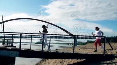 女孩们跑过沙滩上的桥。 头发飘飘，阳光灿烂，蓝天..