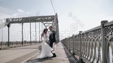 疯狂的一对新婚夫妇手里拿着伞在桥边跳舞。