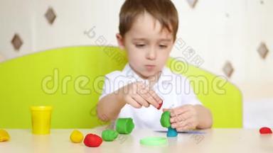 这个孩子在餐桌上玩得很开心，做着特写，玩着用<strong>橡皮泥</strong>或面团做的多色造型