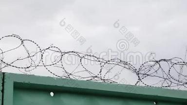 监狱里铁丝网的特写镜头。 带刺铁丝网的监狱。 带刺铁丝网的绿色围栏