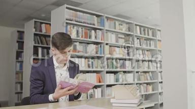 年轻的男学生在图书馆看书。 在书架背景上穿西装看书的人。
