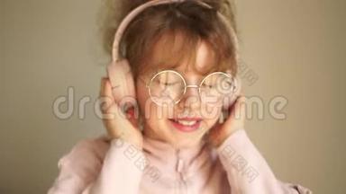 一个戴着耳机戴着眼镜的十几岁女孩的肖像。 女孩用耳机听音乐，跳舞
