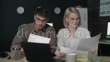 一对商务夫妇在夜班办公室使用文档数据前置笔记本电脑