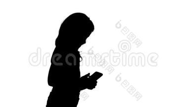 小女孩走路的时候在玩智能手机。