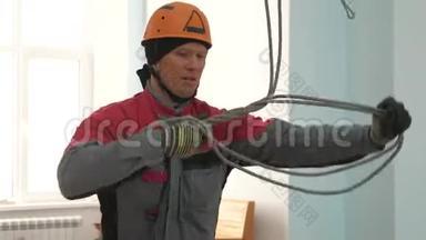 工业登山者为起重设备编织绳索。 戴防护头盔的工人在绳子上<strong>打结</strong>。