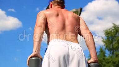 运动动机。 在一个阳光明媚的日子里，肌肉发达的运动员在户外的<strong>高低</strong>杠上扭动身体. 健康的生活方式、身体