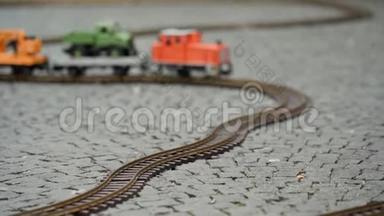 多种颜色的货运列车模型沿着铁路的缠绕轨道行驶。 靠近侧面地面