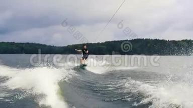 极限水上运动。 年轻人在湖边的尾灯上玩把戏。 滑雪板骑手在水中快速移动