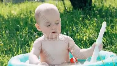 夏日里，小男孩在充气游泳池里玩耍，微笑