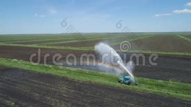 农田灌溉系统。 一大股水流灌溉田地.. 一辆拖拉机正在给一块田地浇水.