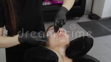 美容院的专业美容师用特殊的电影闭上客户的眼睛。