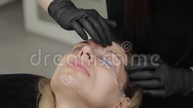 美容院的专业美容师用特殊的电影闭上客户的眼睛。