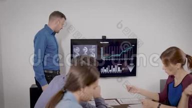 在办公室<strong>报到</strong>.. 一个人以自己的方式为同事做演讲。 商业幻灯片显示在电视上。