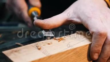 木工行业-一名木工用凿子和他的手切割<strong>木器</strong>上的凹槽