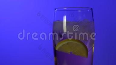 在彩色蓝色背景特写镜头上装有<strong>饮料</strong>的玻璃杯，反光灯，<strong>柠檬</strong>，<strong>冰</strong>