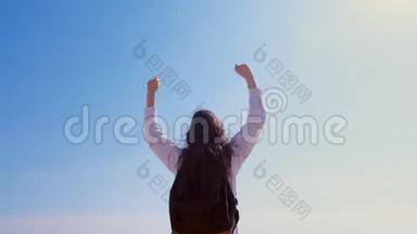 女胜者在胜利的姿态与举手的天空背景后景。