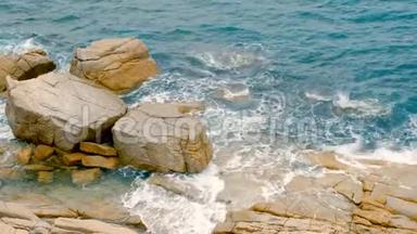 海浪拍打在岩石上，泡沫般的海浪来到海岸，蓝色的海水和山丘，在白天