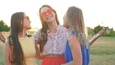在温暖的夏日里，三个朋友在街上拥抱的快乐会议。 三个女孩戴着太阳镜，<strong>身材矮小</strong>