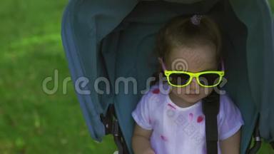 特写：可爱的女孩看着坐在蓝色婴儿车里的镜头微笑-家庭<strong>价值观</strong>温暖的色彩夏天的场景