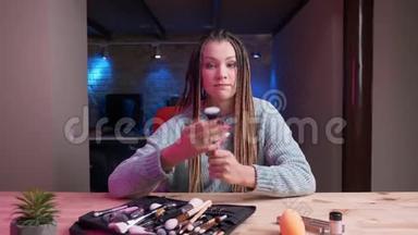 年轻迷人的女化妆师的特写镜头，用恐怖片流媒体直播和广告化妆品与恐怖片