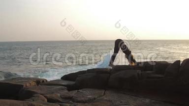 <strong>身穿</strong>黑色<strong>运动服</strong>的女士站在岩石悬崖上做瑜伽姿势