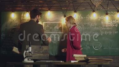 胡子教授和女学生决定黑板上写的公式。 旁边的教授和学生