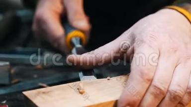 木工行业-一名木工用凿子和他的手把木器上的凹处凿出来