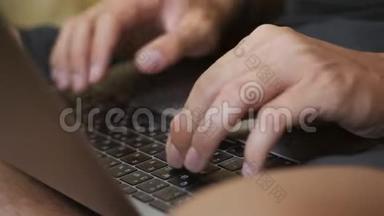 一个男人的手`笔记本电脑的键盘上。 一个年轻人坐在地板上用电脑工作。