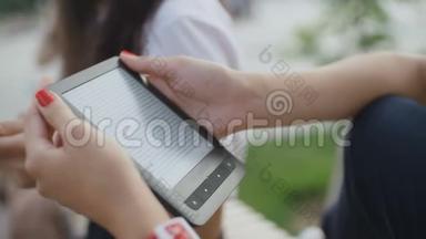 女人`手拿着公园里的电子书