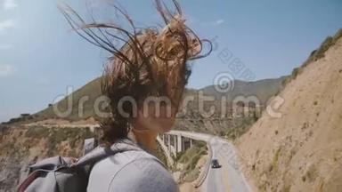美丽快乐的年轻女子，带着飞扬的头发，微笑着，在大苏尔比桥的<strong>观察点</strong>对着镜头摆姿势。