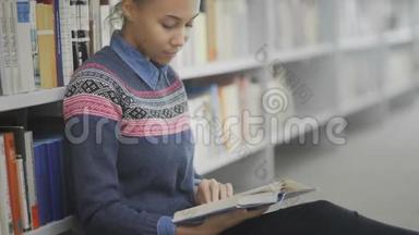 非裔<strong>美国</strong>妇女多利搬家正坐在学校<strong>图书馆</strong>的地板上看书。