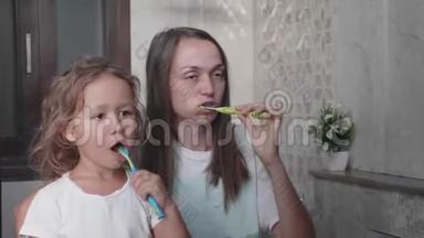 妈妈和她可<strong>爱</strong>的小女儿正在一起用<strong>牙</strong>刷刷<strong>牙</strong>。