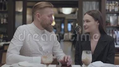 成熟的男人在餐厅的桌子上给一个漂亮的年轻女人讲故事。