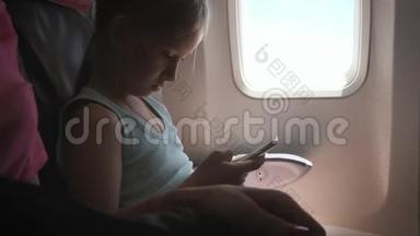 可爱的女孩乘飞机旅行，在飞行中使用数字平板电脑。 与孩子一起出国旅行的概念。