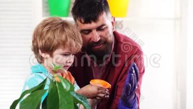 可爱的孩子帮助他的父亲照顾植物。 春观念，自然与关怀.. 抱着幼苗的小孩