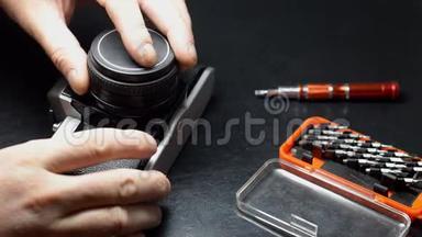 一位修理摄影设备的专家修理一台旧相机。