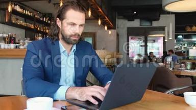 一个年轻的商人用电话坐在咖啡馆的一张桌子旁。 成功人士，日常生活