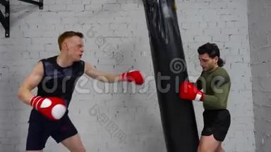 拳击手戴拳击手套的战士在个人训练时在战斗袋上吹气。 健身教练训练男子拳击