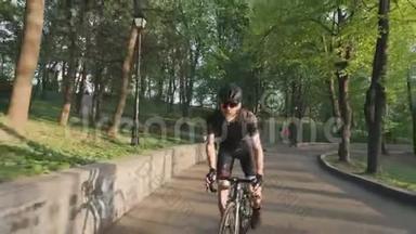 穿着黑色运动服，戴着眼镜和头盔，骑在我们的马鞍上的强壮的自行车运动员。专业自行车运动员