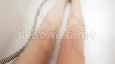 在潮湿的白色<strong>浴缸</strong>里，双腿伸出，用<strong>热水</strong>浇灌膝盖
