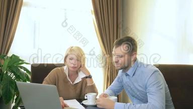 男人和女人坐在办公室，手提电脑前说话