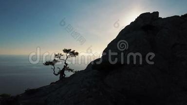 一位年轻女子在日落时<strong>靠海</strong>爬到山顶的剪影。 女士